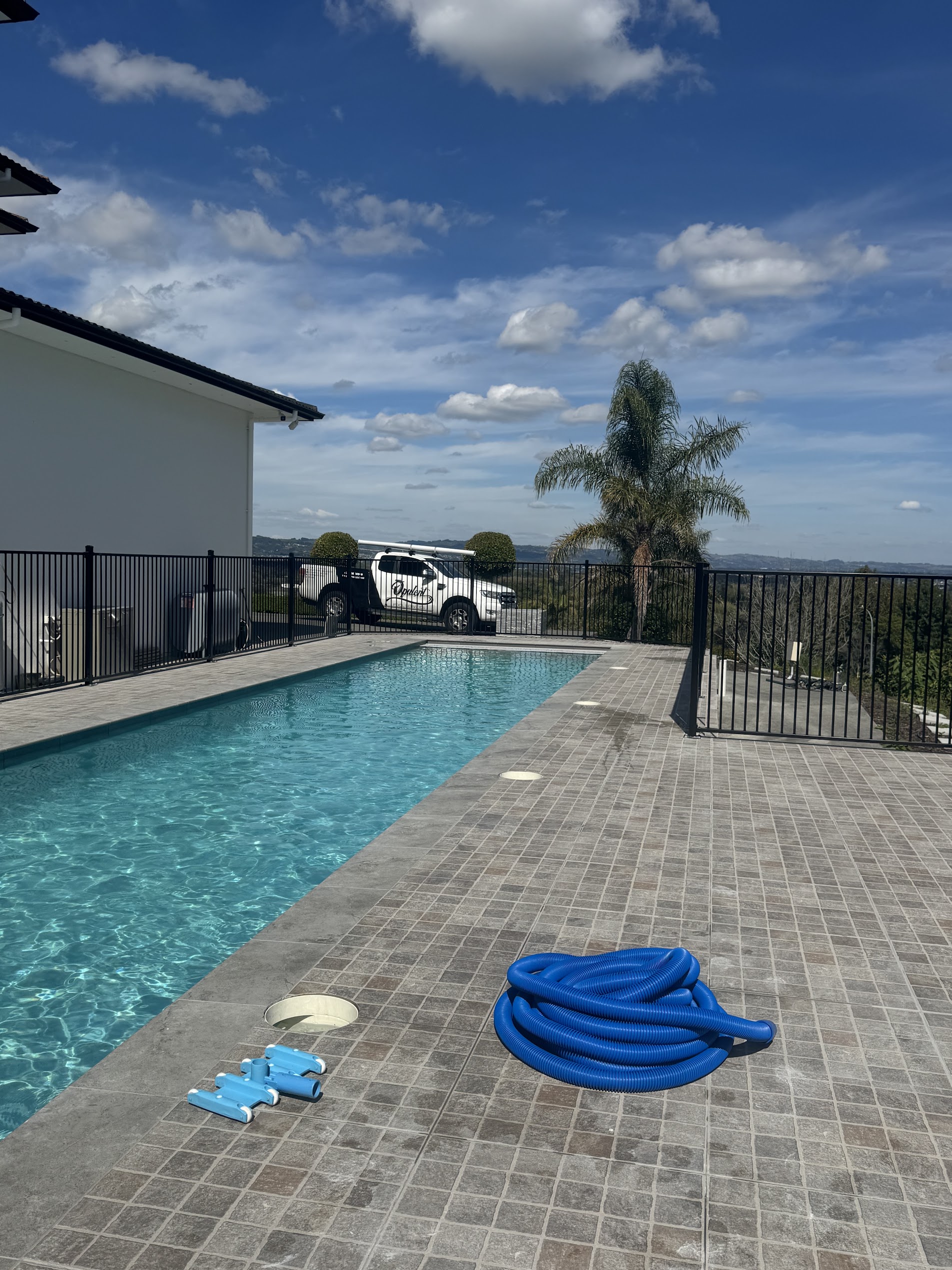 Rectangular pool on a hilltop Auckland property with panoramic views, freshly cleaned with equipment laid out on the deck